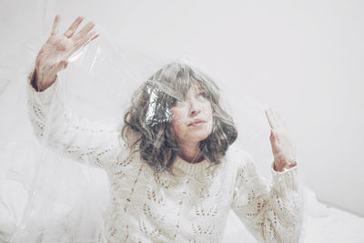 Woman looking up struggling inside plastic in confined space