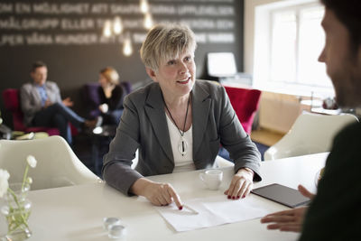 Senior businesswoman discussing with male colleague at office desk