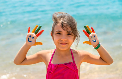 Portrait of smiling girl showing painted hand at beach