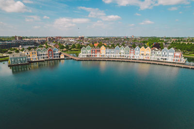Buildings by river against sky