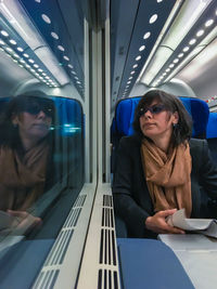 Reflection of woman traveling in illuminated train on window