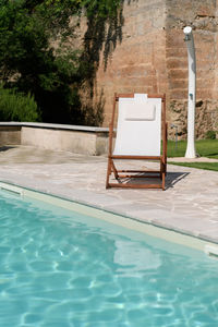 Swim pool with clear blue water and two sun bed on sunny day in a yard, beautiful vacation 