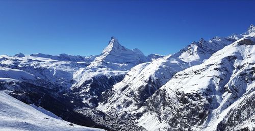 Scenic view of snowcapped mountains against clear blue sky