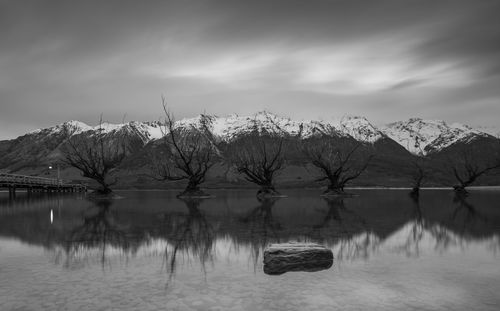 Scenic view of lake by snowcapped mountain against sky