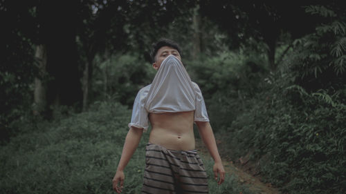 Rear view of woman standing on field in forest