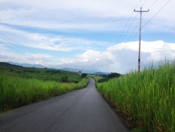 Road amidst field against sky