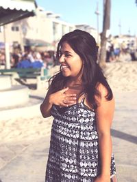 Happy woman looking away while standing at beach