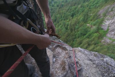 Midsection of man holding rope while standing on mountain