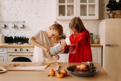 Two teens children are having fun playing, preparing christmas food for the holiday in the kitchen
