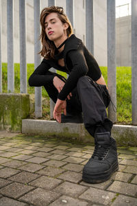 Portrait of young woman sitting on footpath