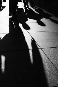 Low section of silhouette woman walking on tiled floor