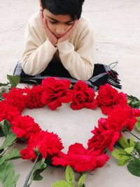 Boy looking at red flowers