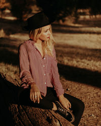 Thoughtful young woman looking away while sitting at park during sunset