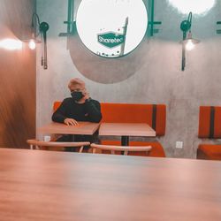 Man and woman sitting on table in illuminated room