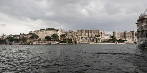 City at waterfront against cloudy sky