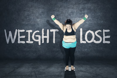 Full length of woman standing against wall