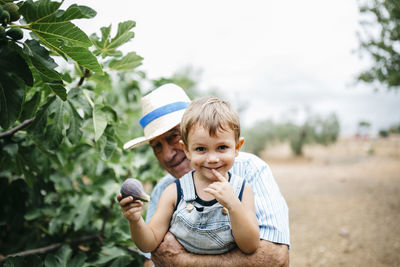 Portrait of happy little boy picking figs with his great-grandfather