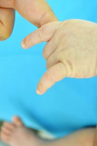 Cropped hand of baby holding parent finger