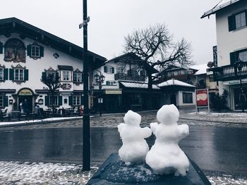 Snow on street by buildings against sky