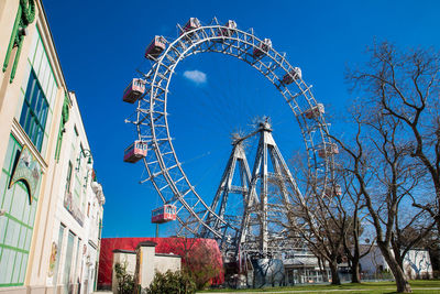 Low angle view of ferris wheel against buildings in city