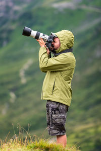 Photographer with telephoto lens in mountain landscape. 