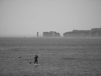 Men standing on shore by sea against clear sky