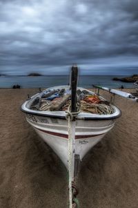 Fishing boat on beach against sky