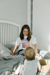 Smiling girl playing with sibling on bed