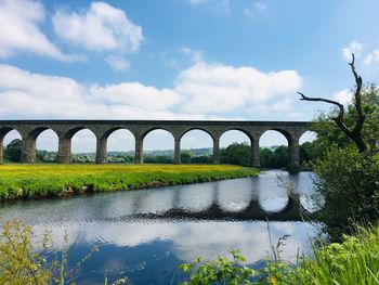 Arch bridge over river against sky