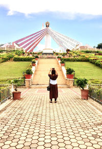 Rear view of woman photographing jesus christ statue against sky