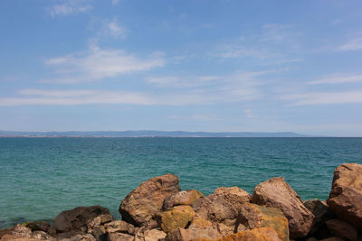 Rocks by sea against blue sky