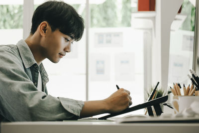 Side view of man sitting on table