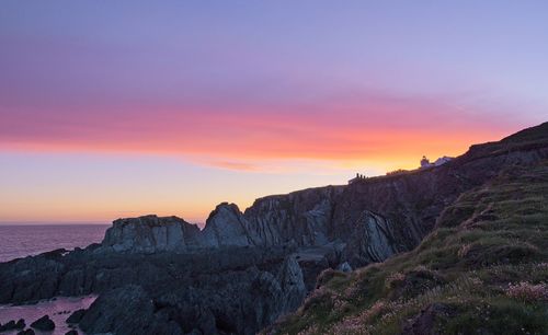 Rock formations on sea against sky during sunset
