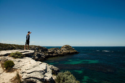 Man standing at beach against blue sky