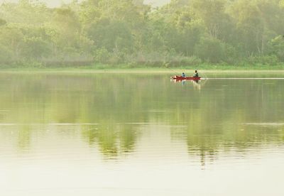 Two people rowing boat in lake