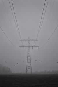 Low angle view of electricity pylons against sky