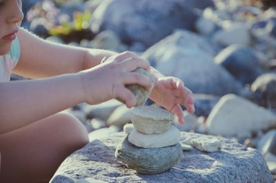 Midsection of girl stacking rocks at beach