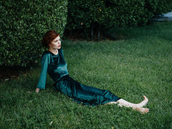 Side view of senior man sitting on grass in field