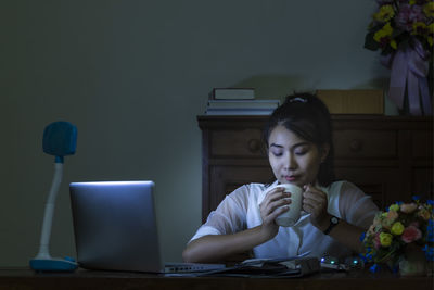 Woman looking at camera while sitting on table