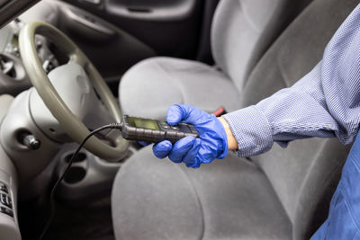 Midsection of man holding umbrella in car