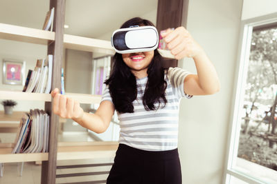 Smiling woman using virtual reality simulator while standing at home