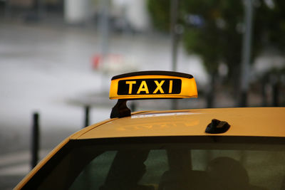 Close-up of yellow sign on taxi roof