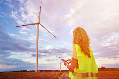 Woman holding umbrella while standing on land against sky