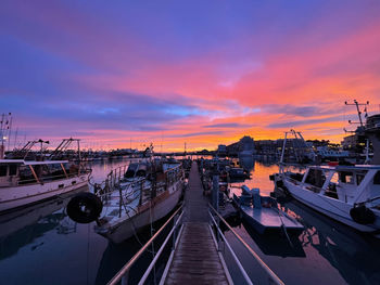 Boats moored at harbor during sunset