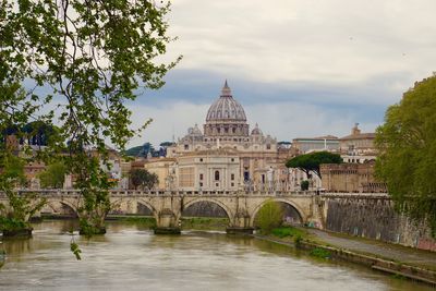 Arch bridge over river against cloudy sky