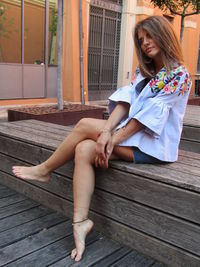 Full length of woman sitting on wooden floor