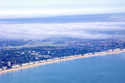 Aerial view of city by sea against sky