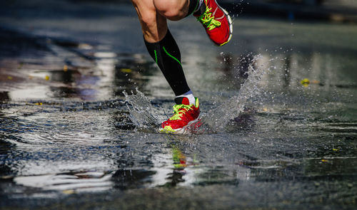 Runner legs in compression socks run a puddle, splashing water	