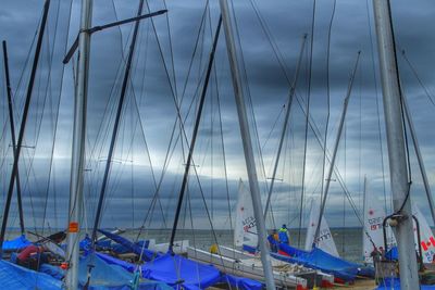 Sailboats moored in sea against sky