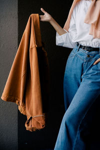 Low section of woman holding hands against wall